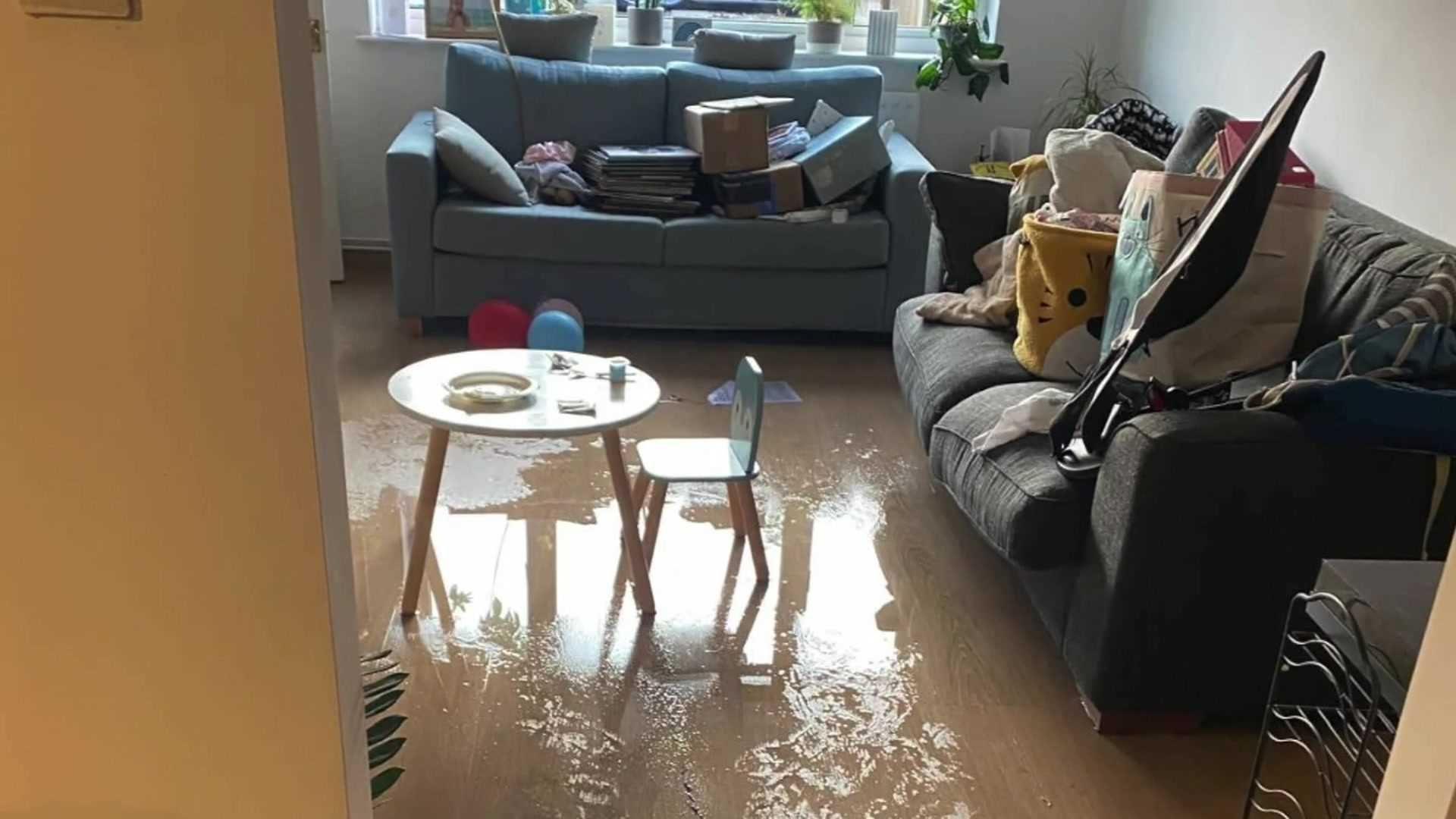 Water covering the living room floor and items on the sofa for safe keeping