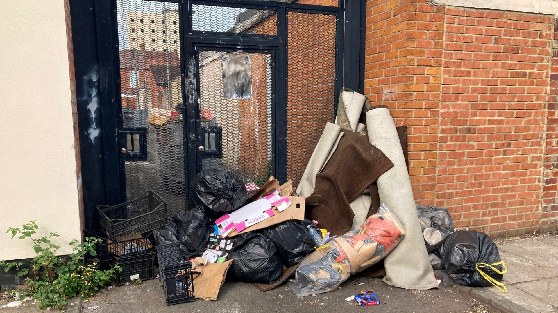 Bags of rubbish, rolled up rugs and boxes left on a street