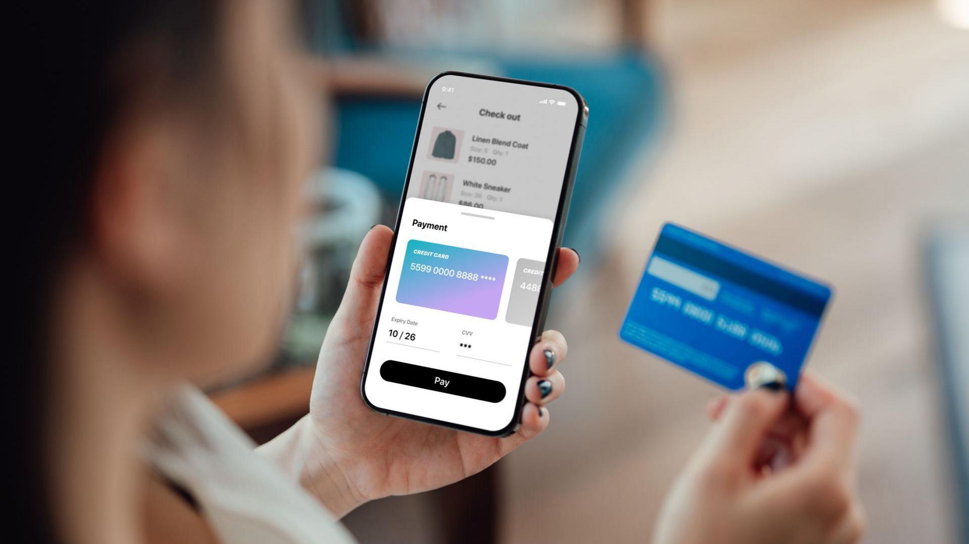 Stock image of a woman holding a phone and a bank card