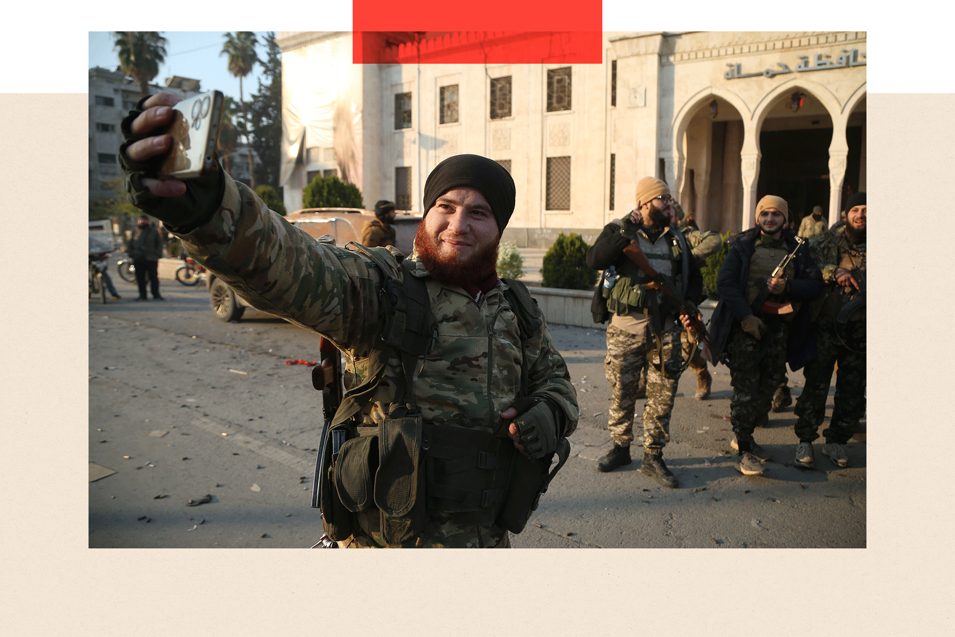 A rebel fighter snaps a selfie with comrades standing in the background