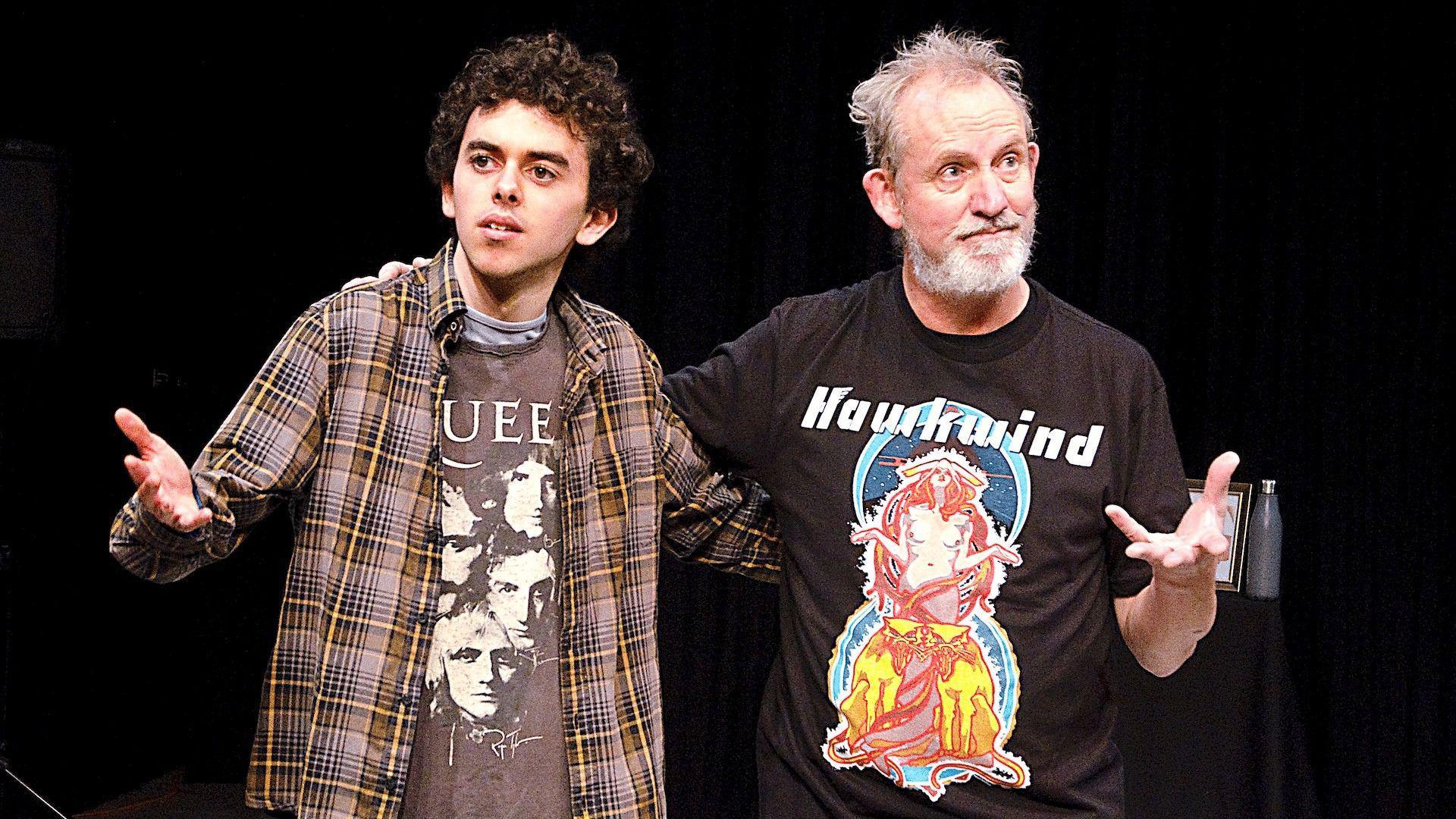 Luca on the left is wearing a Queen t-shirt covered by a chequered flannel shirt. Philip is wearing a t-shirt which is black and says hawkwind on it.