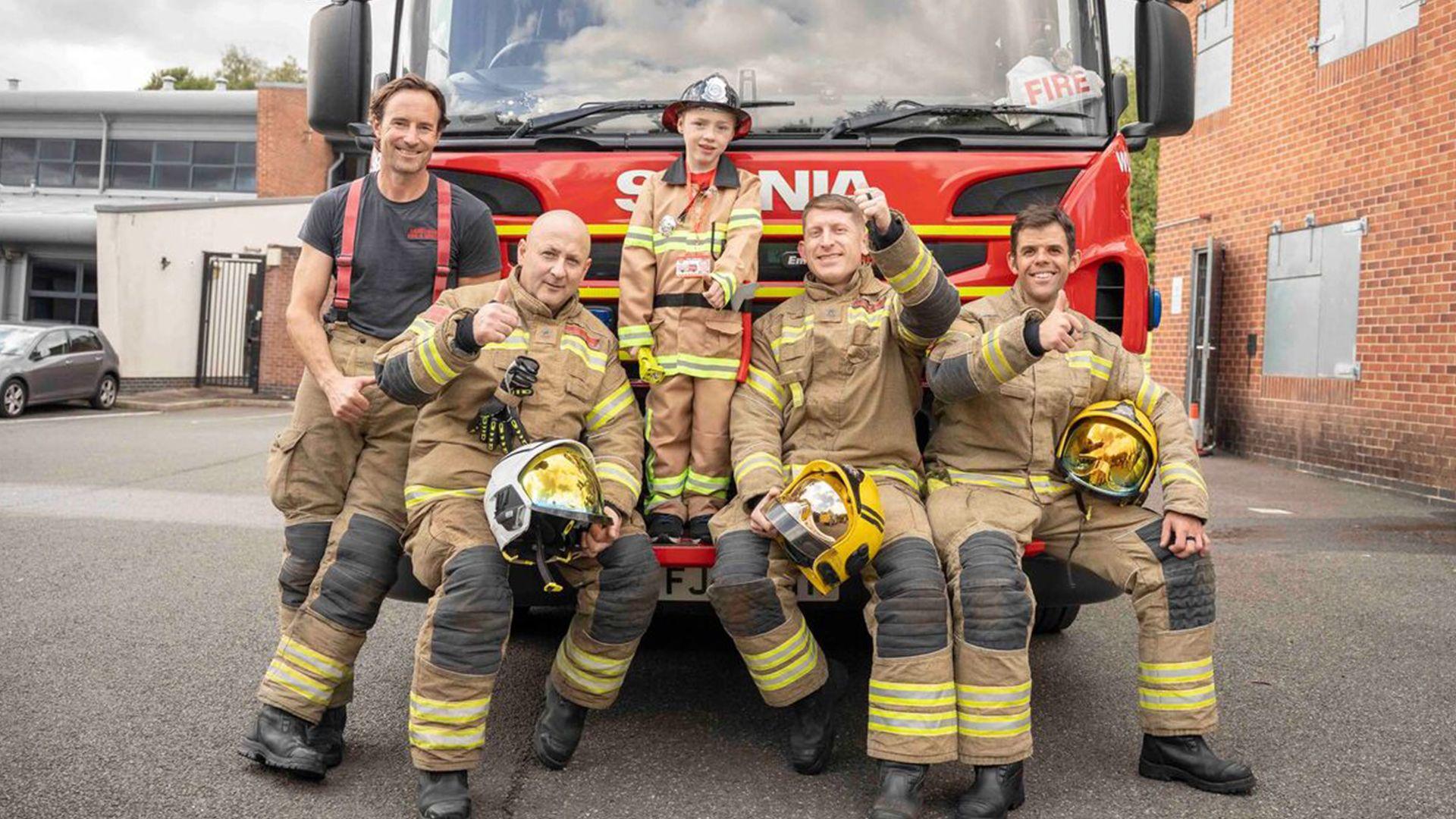 Elliott standing on a fire truck with firefighters from Derbyshire Fire and Rescue Service standing around him