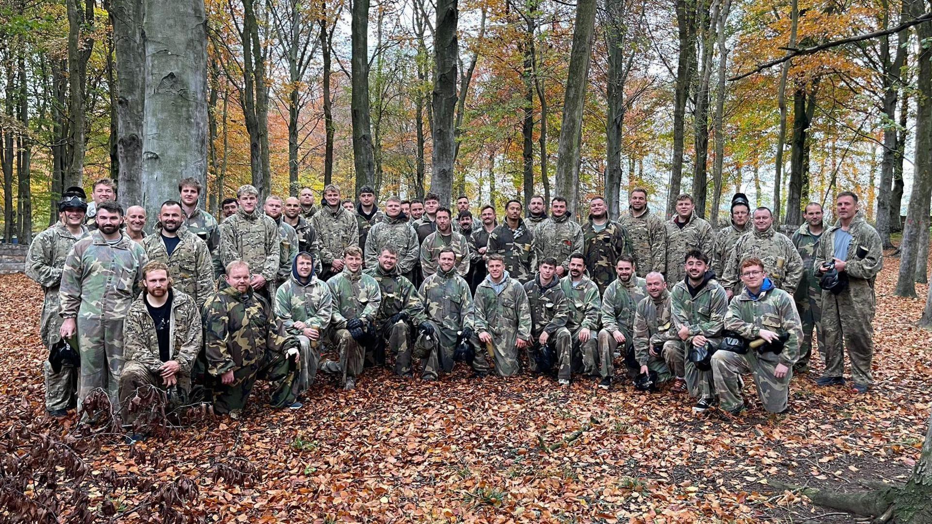 The whole Newcastle Red Bulls squad in paintball combat wear in woods