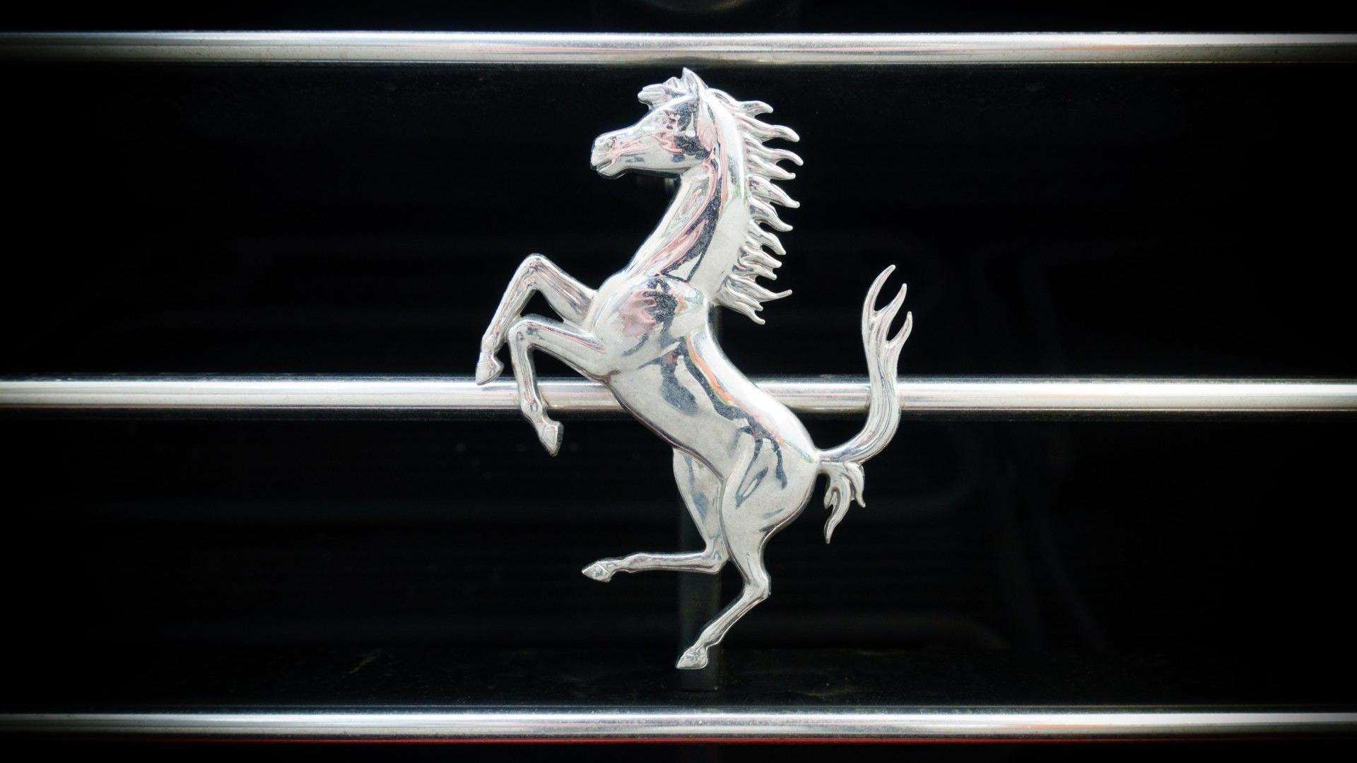 Close up of the silver Ferrari horse logo against a black backdrop