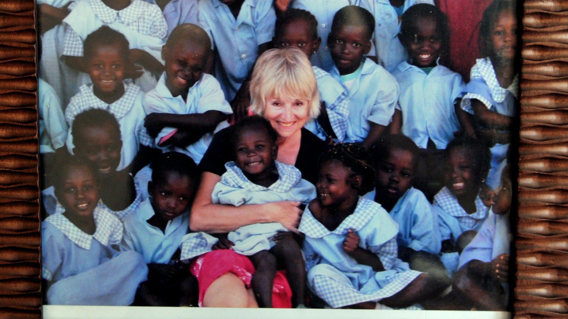 Organ donor Adrienne Fry is pictured cuddling school pupils in Gambia, wearing school uniform.