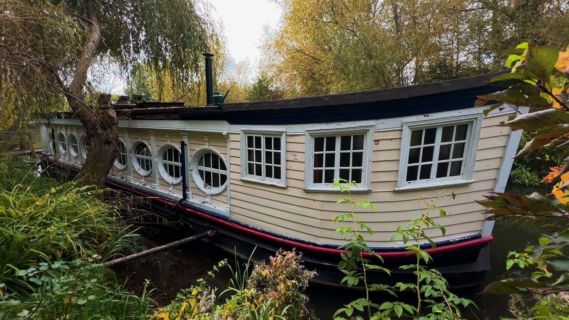 A white barge on a river surrounded by green vegetation.