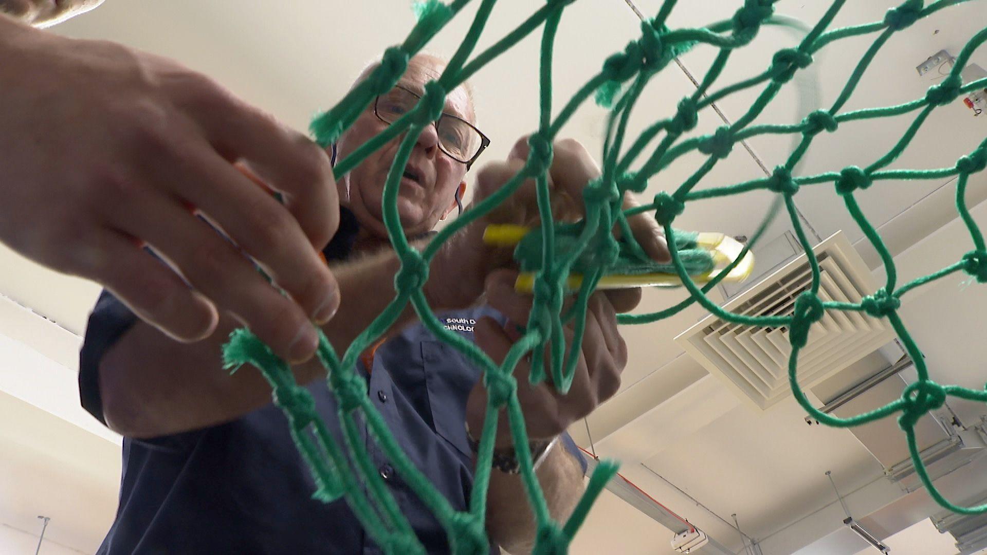 A college tutor demonstrating to a commercial fishing student how to thread a fishing net  at South Devon College