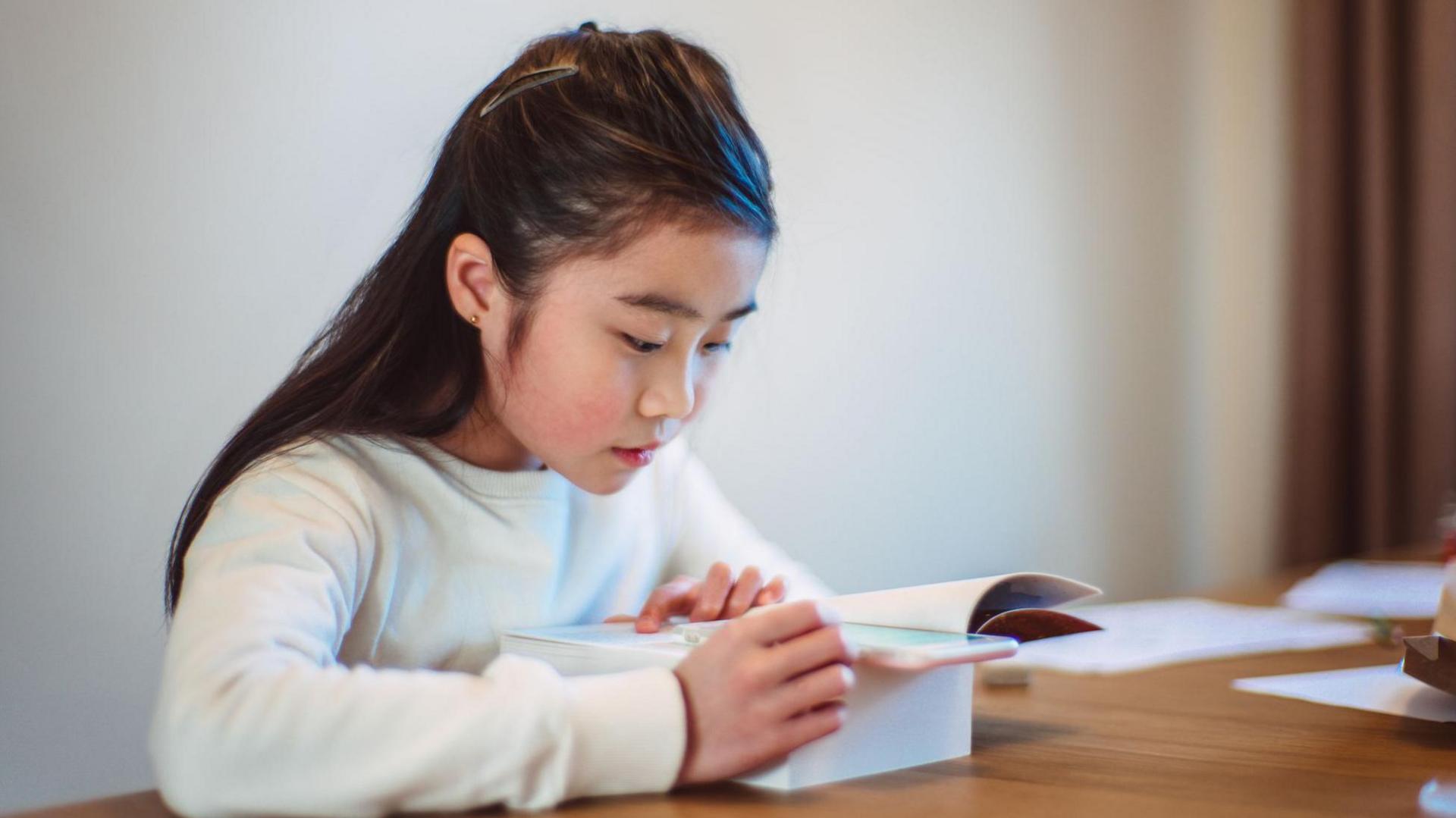 Girl checking words on her phone while reading