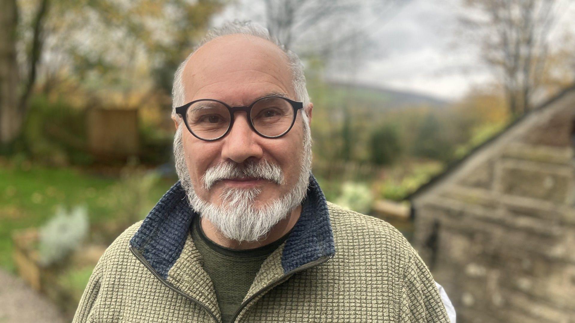 Hollingworth resident Shaheen Naz has a grey trimmed beard and wears round, black-framed glasses.