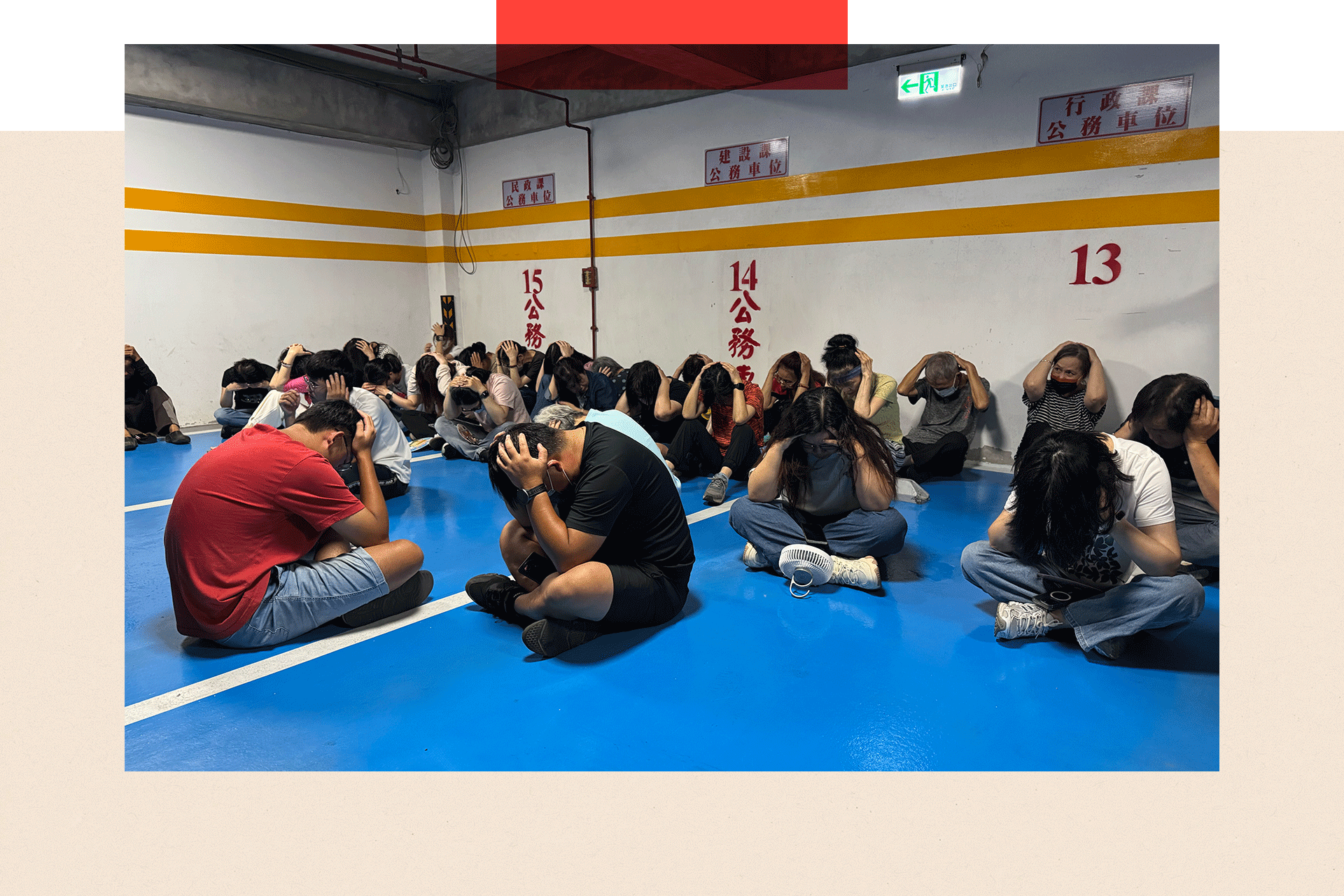 People in Kinmen with their hands over the heads sitting on the floor, as part of one of the drills