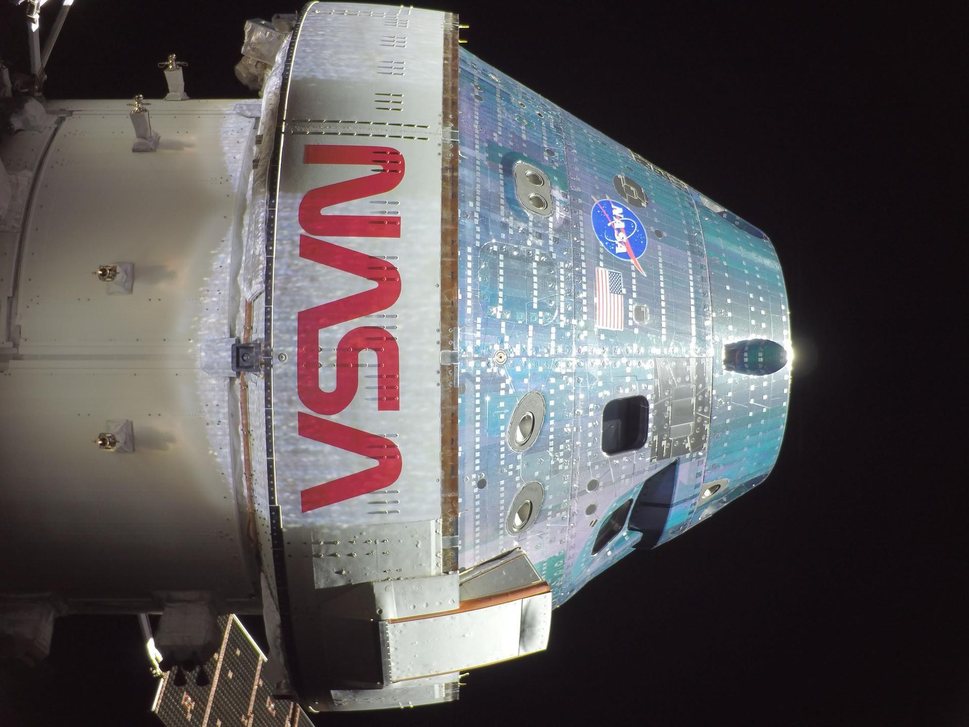 A white cylindirical spacecraft in the blackness of space. Nasa is wriotten in large letters on its side