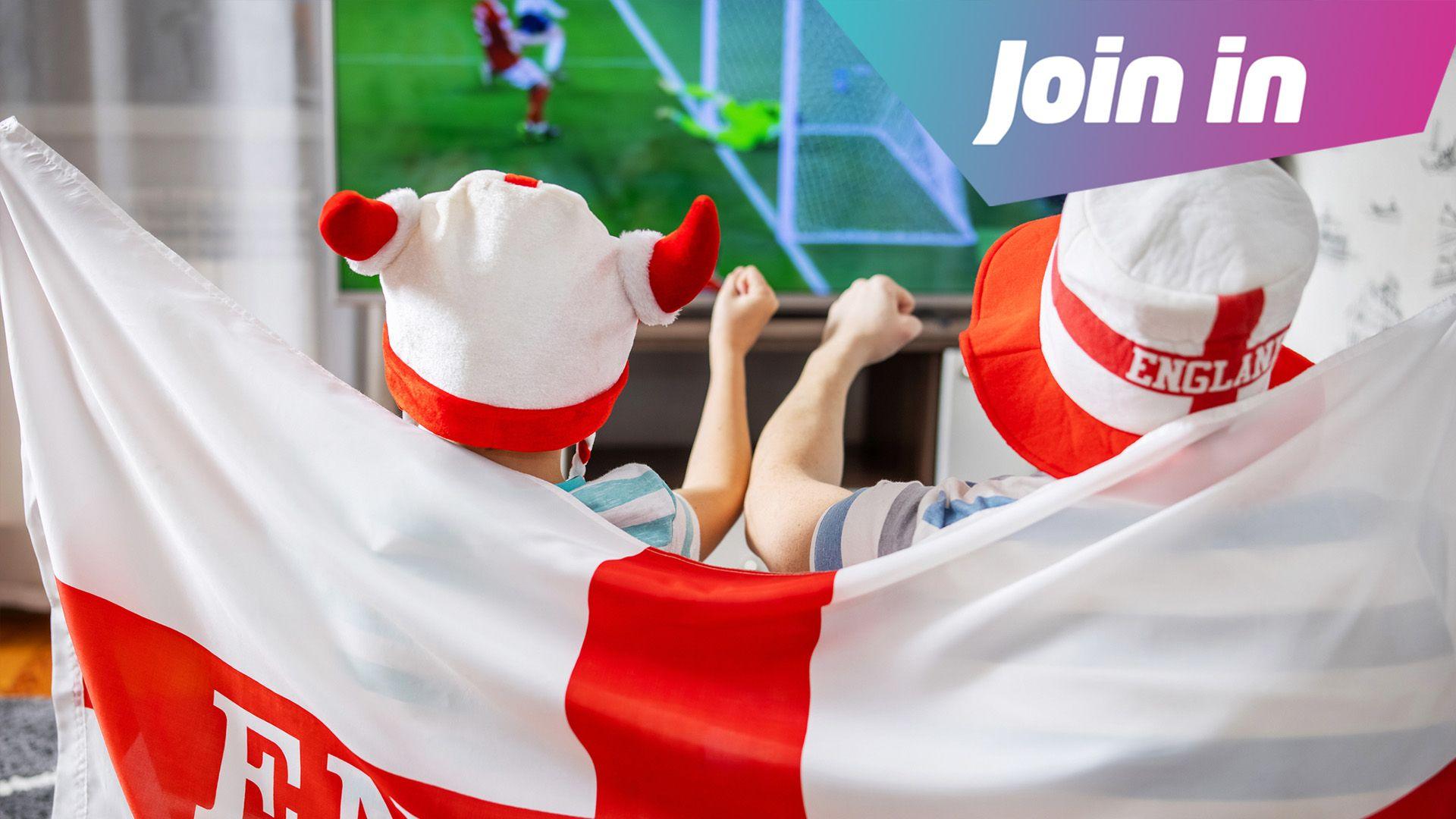 Dad and son watch England football with flag and hats.