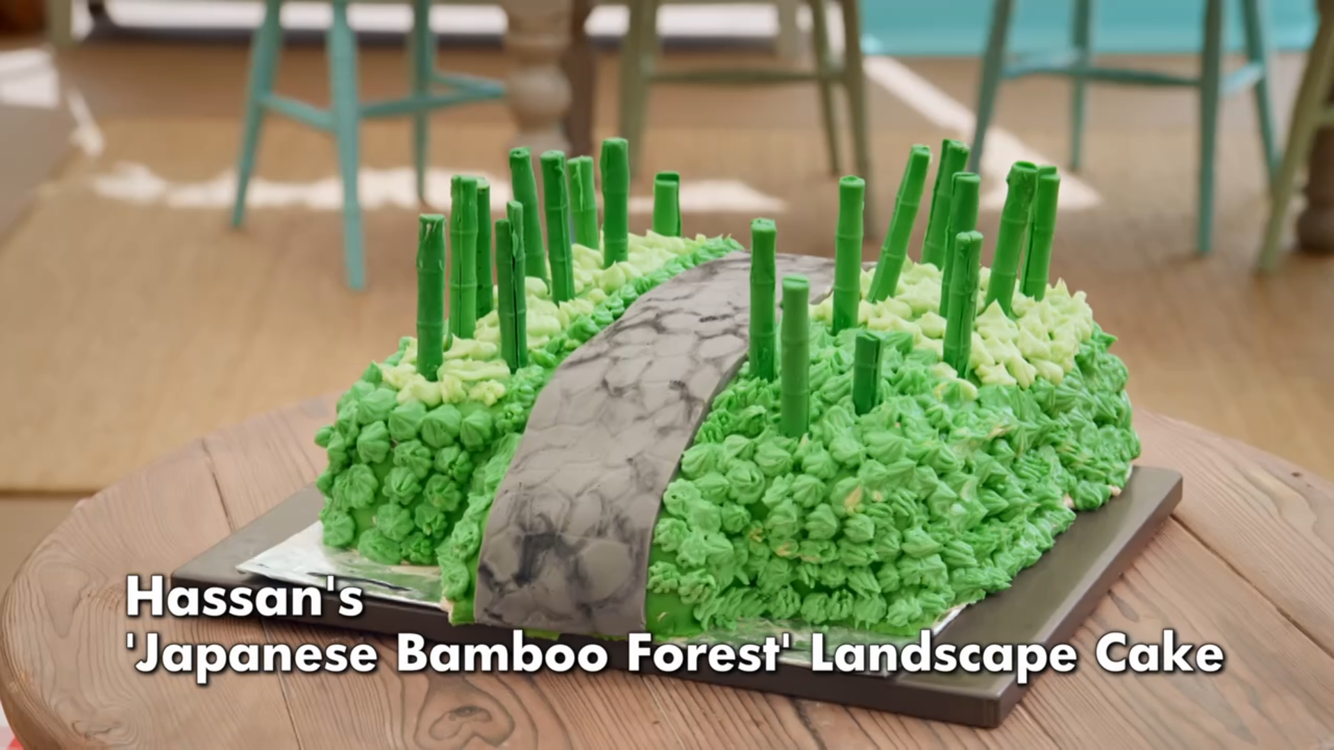 Hassan's Japanese bamboo forest-themed cake. Icing has been used to create a grey path with green swirls either side, and short bamboo plants rising upwards.