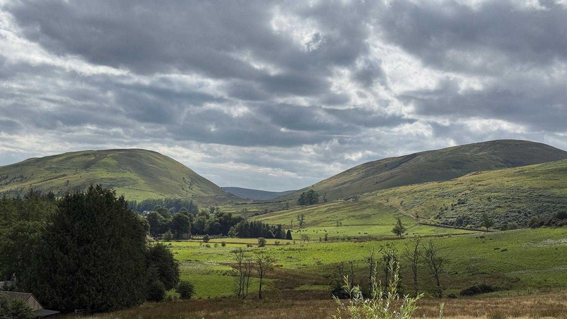 Grey clouds over rolling green hills in Dumfries.