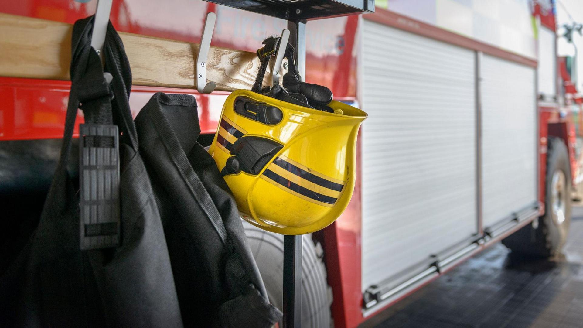 A firefighter's yellow helmet has been hung up on the side of a fire engine.