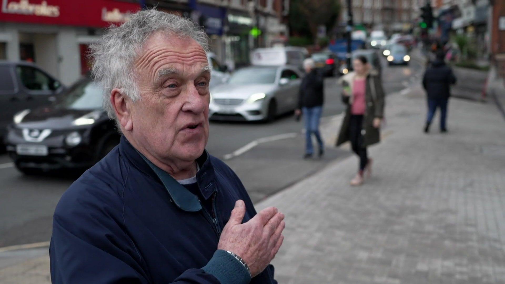 A man looks cross and gesticulates at a pavement