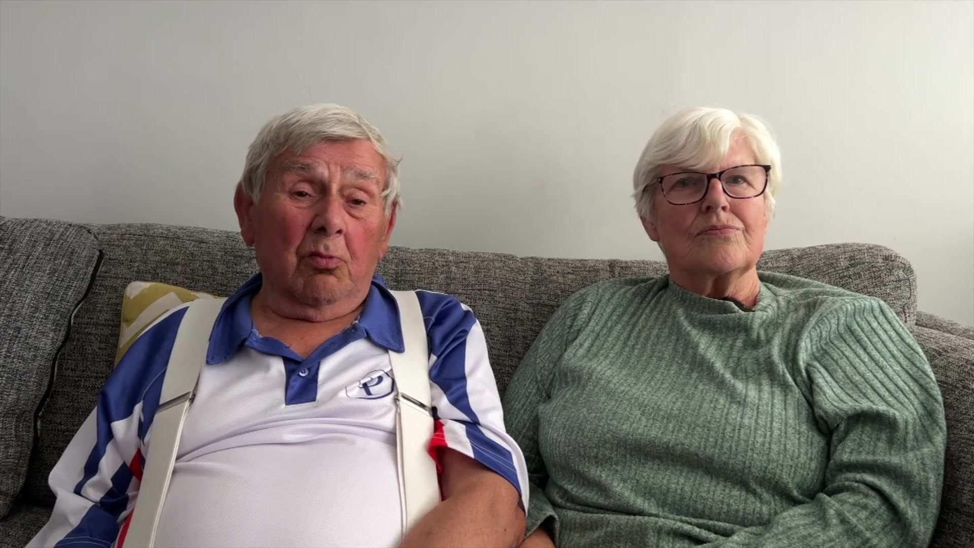 Colin and Anna Froud sitting on a sofa, Colin wears polo shirt and Anna has green jumper