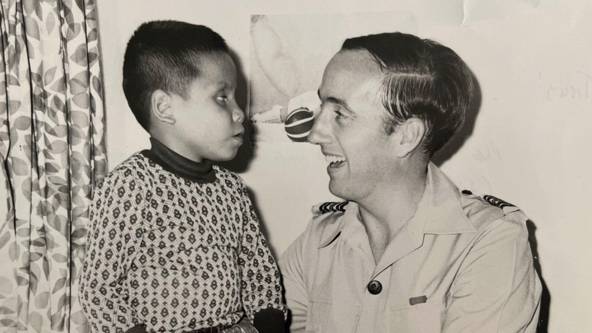 Black and white photo of a boy facing a smiling man in uniform.