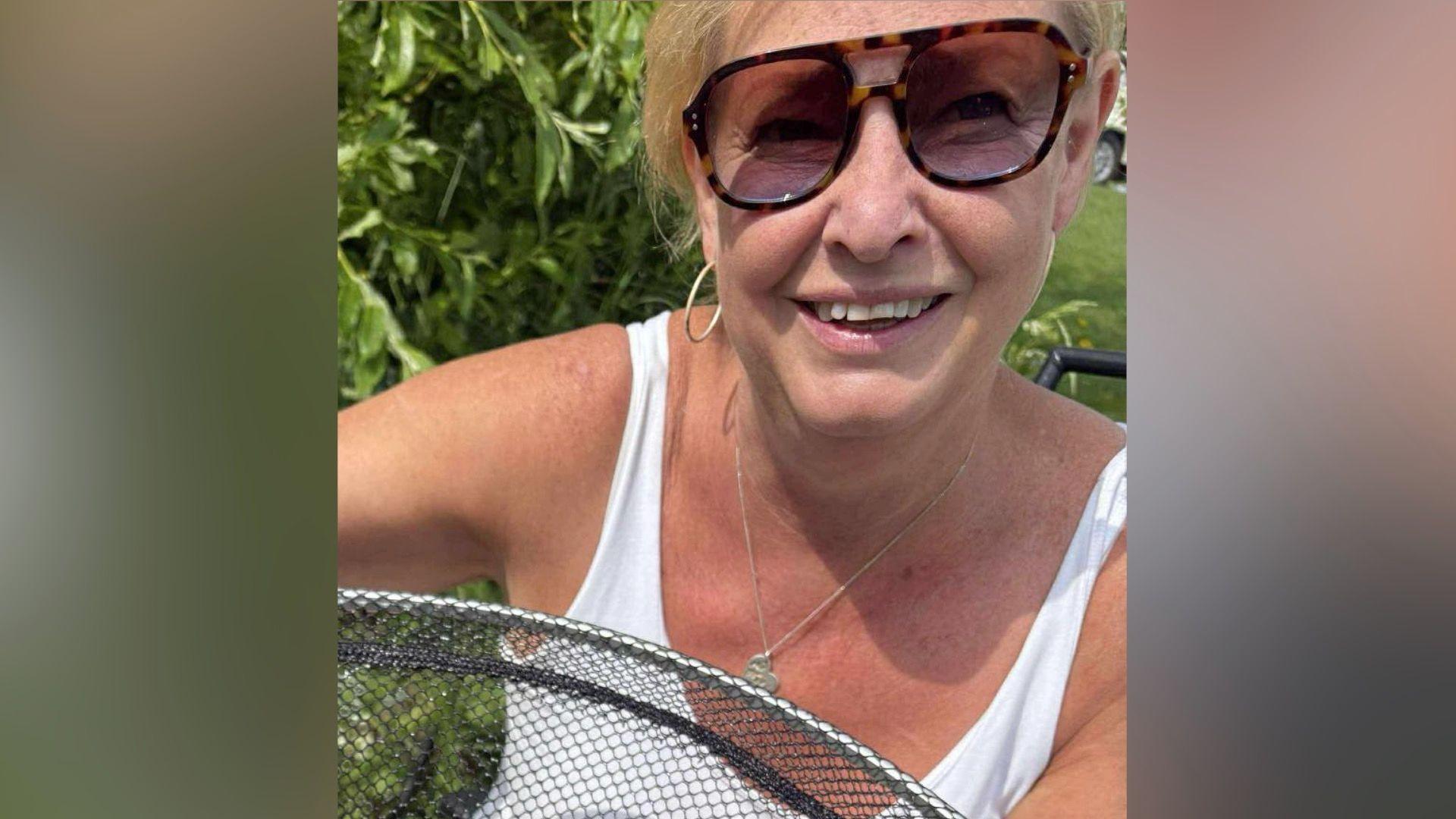 A woman with blond hair and sunglasses smiles for the camera