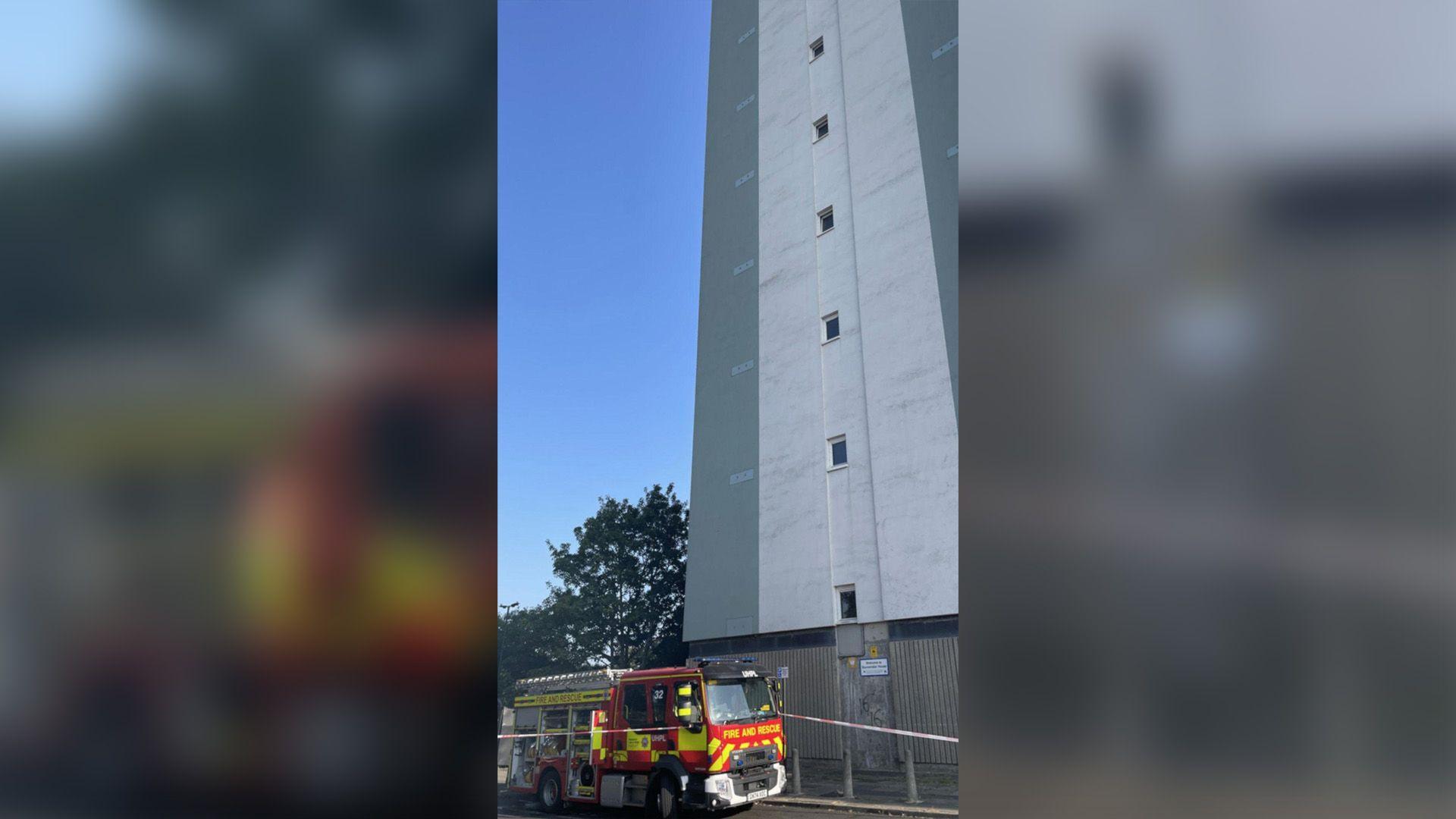 Fire engine and cordon around the bottom of a high-rise block of flats.