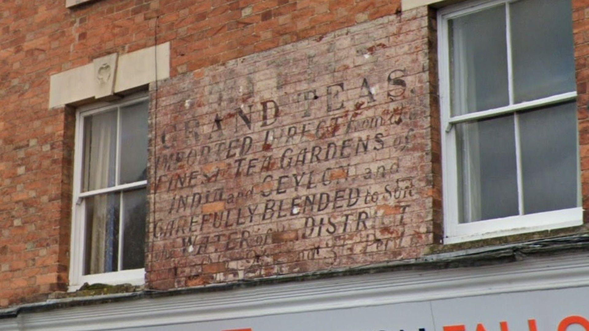 A sign reading 'Grand Teas' on the side of a building in Oakham