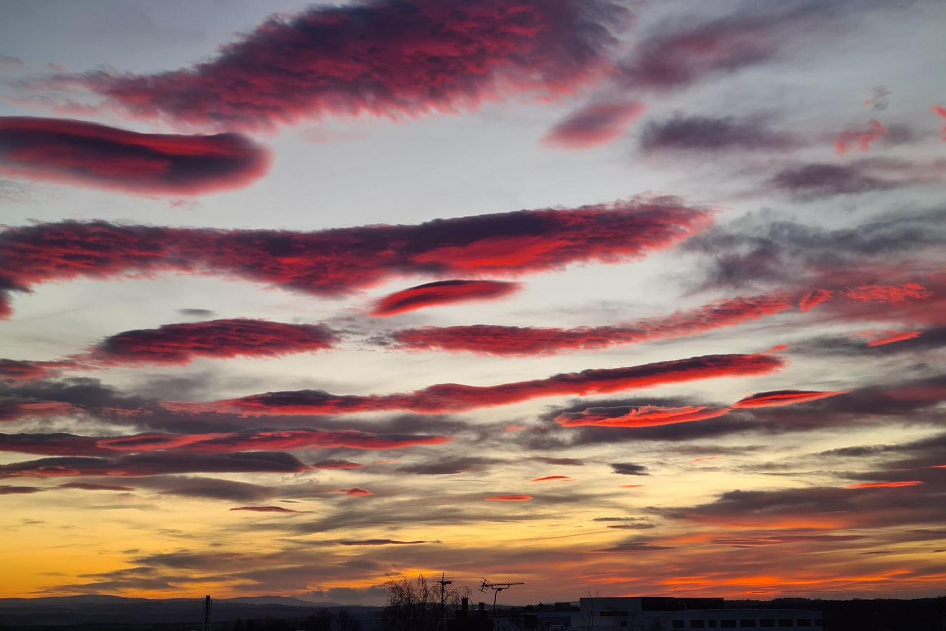 Long lines of cloud glow pink and red.