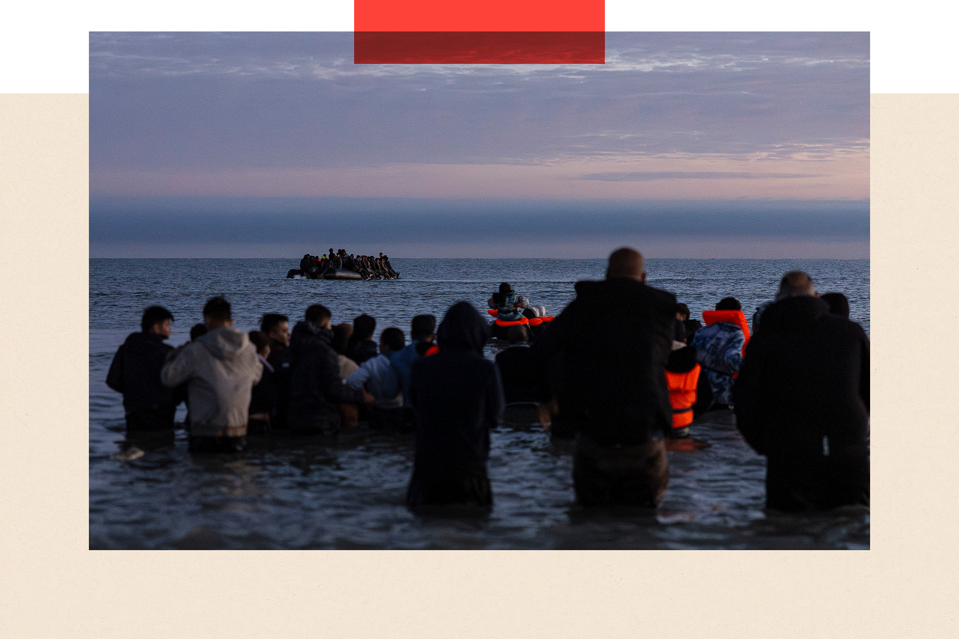 Migrants wait in the water to board a boat across the English Channel