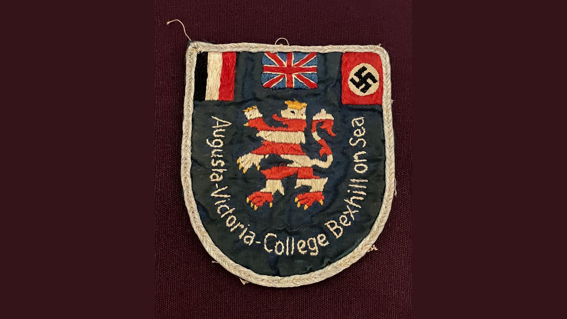 The Augusta Victoria College blazer badge which features an Union Jack, Swastika, a red and white lion rampant.
