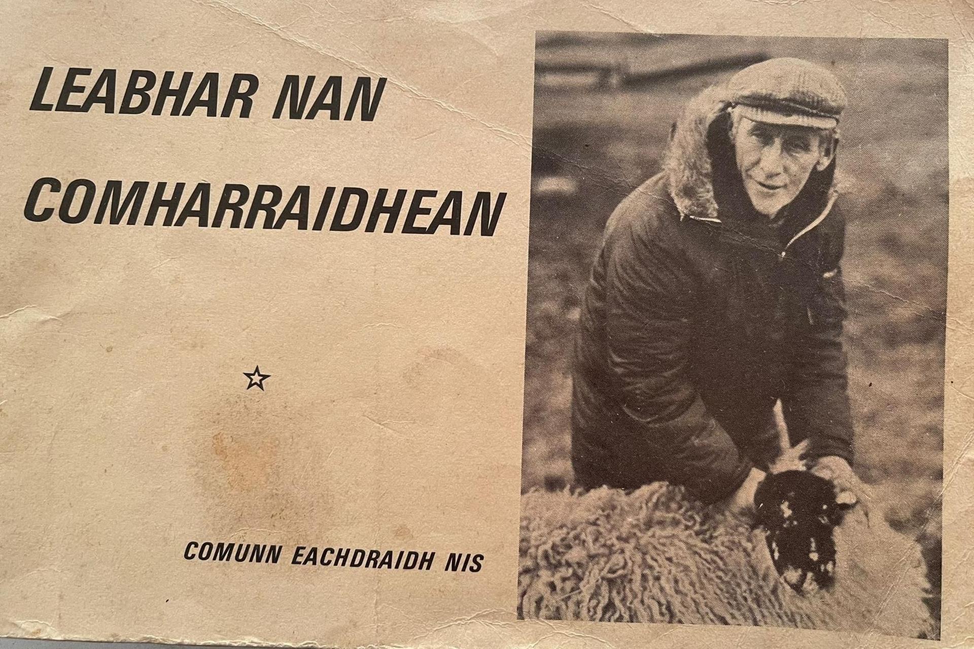 The cover features a crofter wearing a thick winter coat and flat cap. He is holding a woolly sheep. On the cover are words in Gaelic.