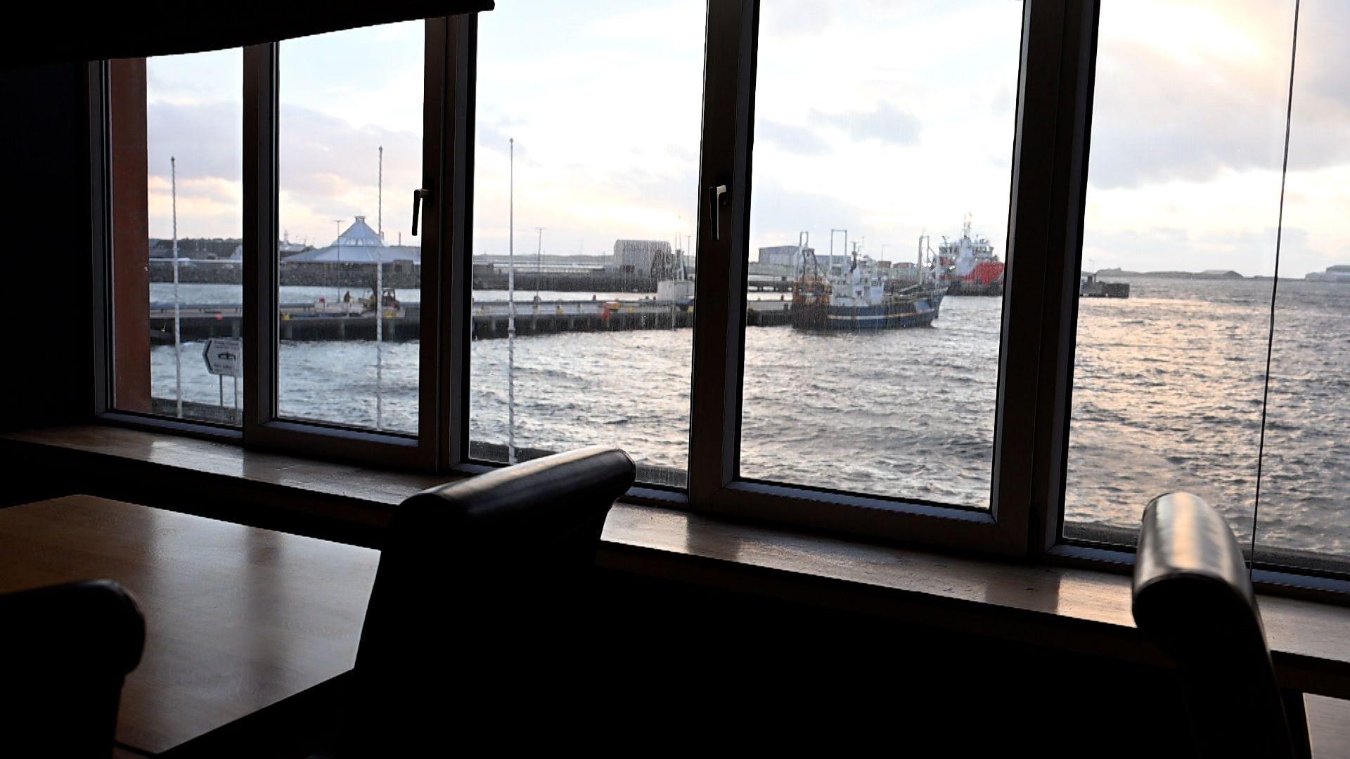 Sealladh air cidhe Steòrnabhagh a-mach air uinneagan an taigh-òsta.