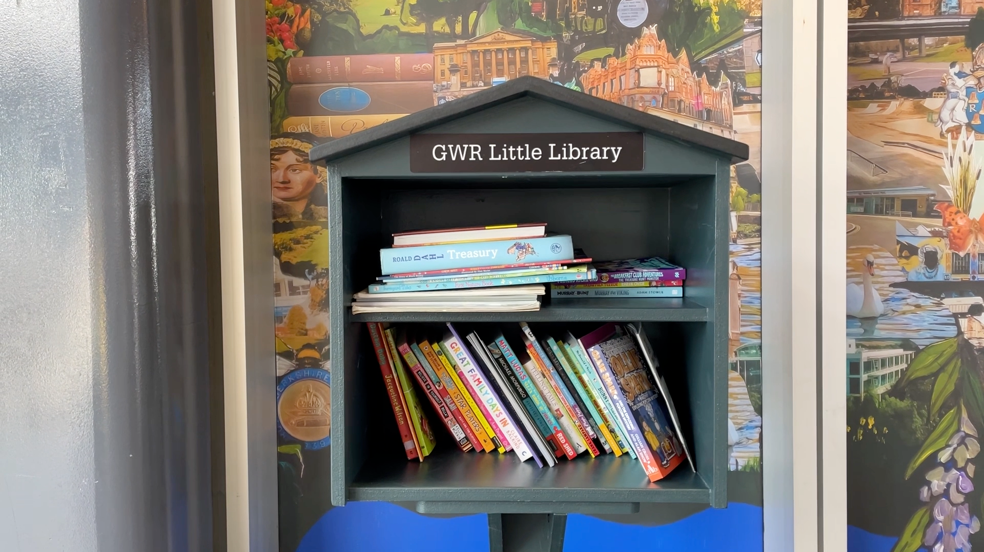A wooden structure can be seen with two shelves and with books on both levels. It has the title GWR Little Library on it.