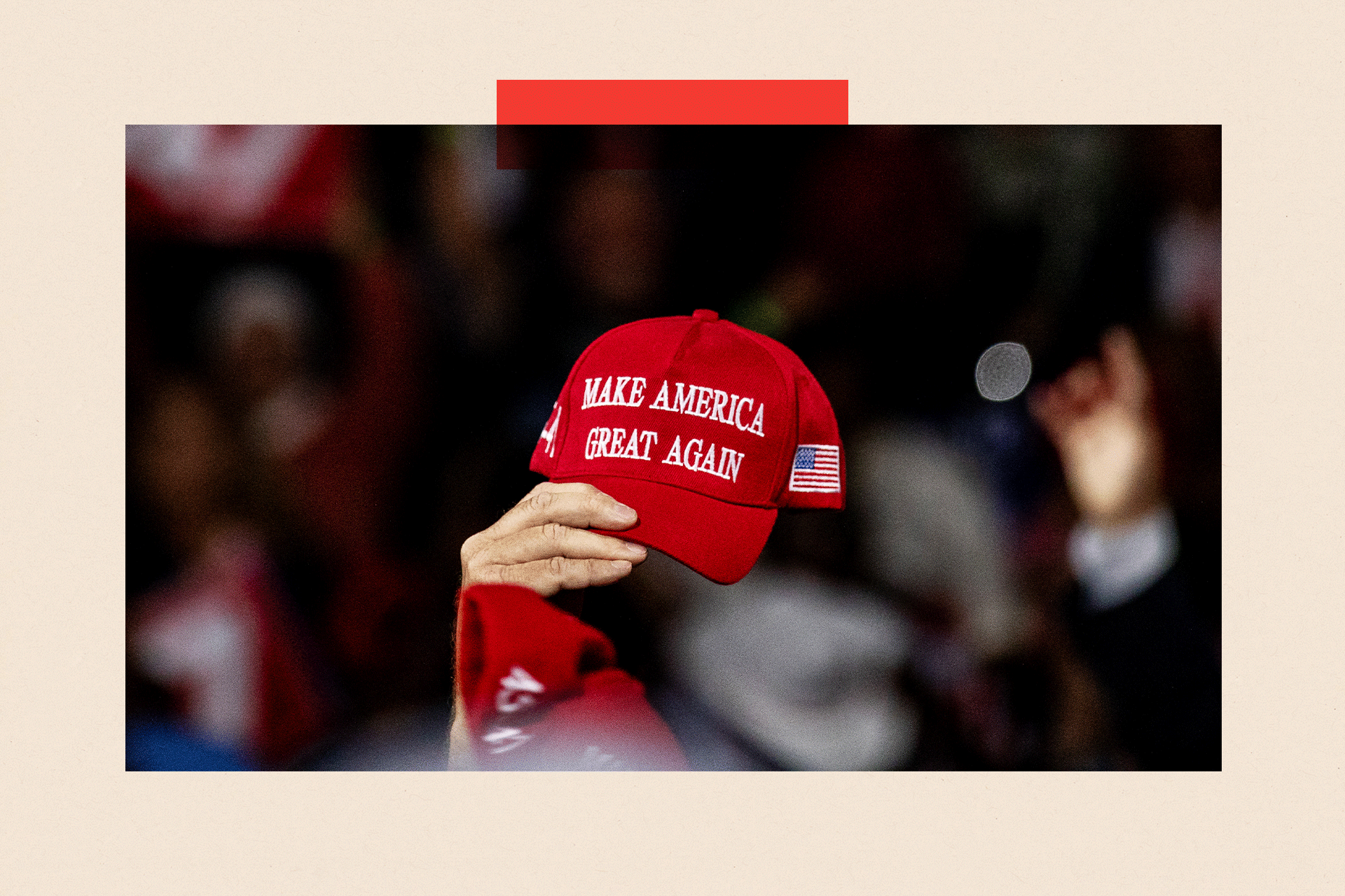 A close up of a person holding a red hat that reads 'Make America Great Again'