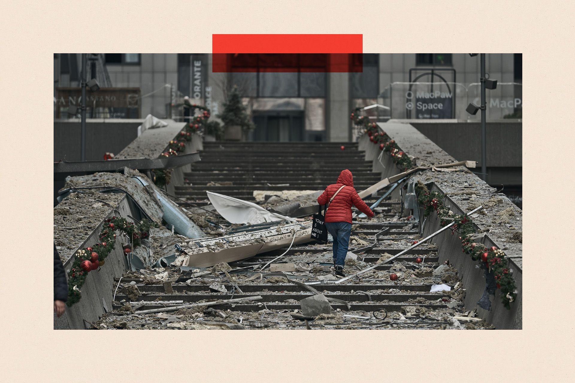 A woman in a red coat climbs damaged steps after a Russian ballistic missile attack on Kyiv, Ukraine