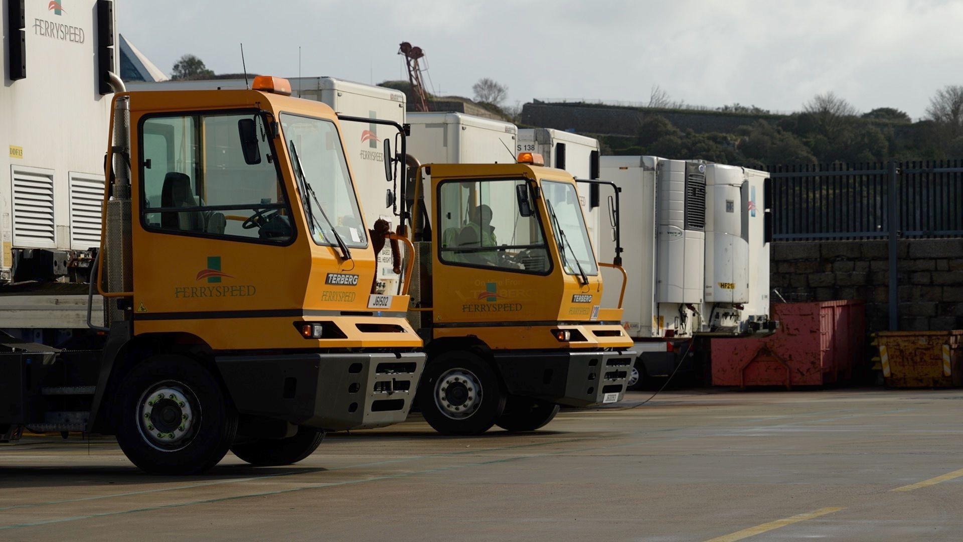 Two ferry speed vans in a car park. The front of the vans is yellow and the back is white 