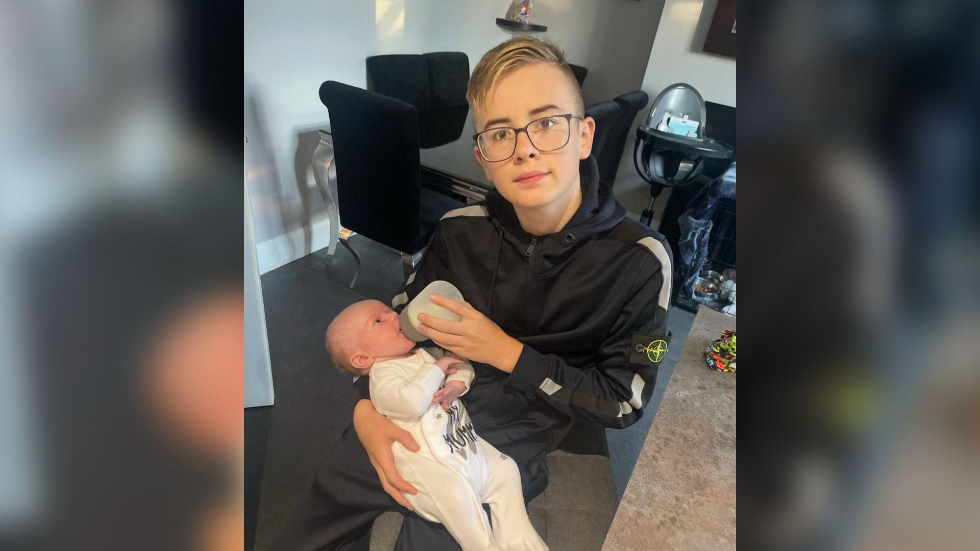 Baby Lyndon being bottle fed by his big brother Lewis Butler inside their home.