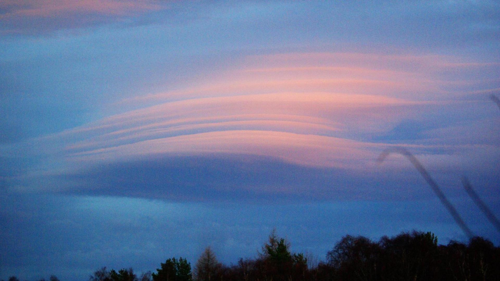 The cloud appears as layers stacked on top of one another and are pale pink and blue.