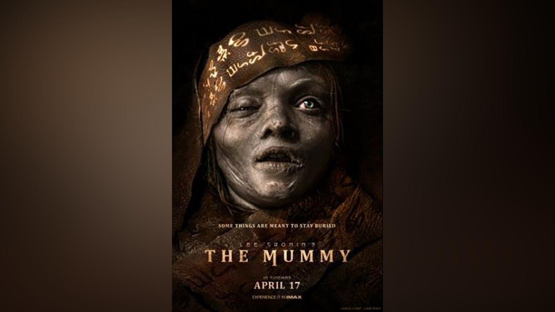 A dark movie poster showing a close-up of a mummified figure with grey, decaying skin, cracked lips, and one eye swollen shut. The head is wrapped in patterned fabric covered in symbols. Text across the bottom reads: