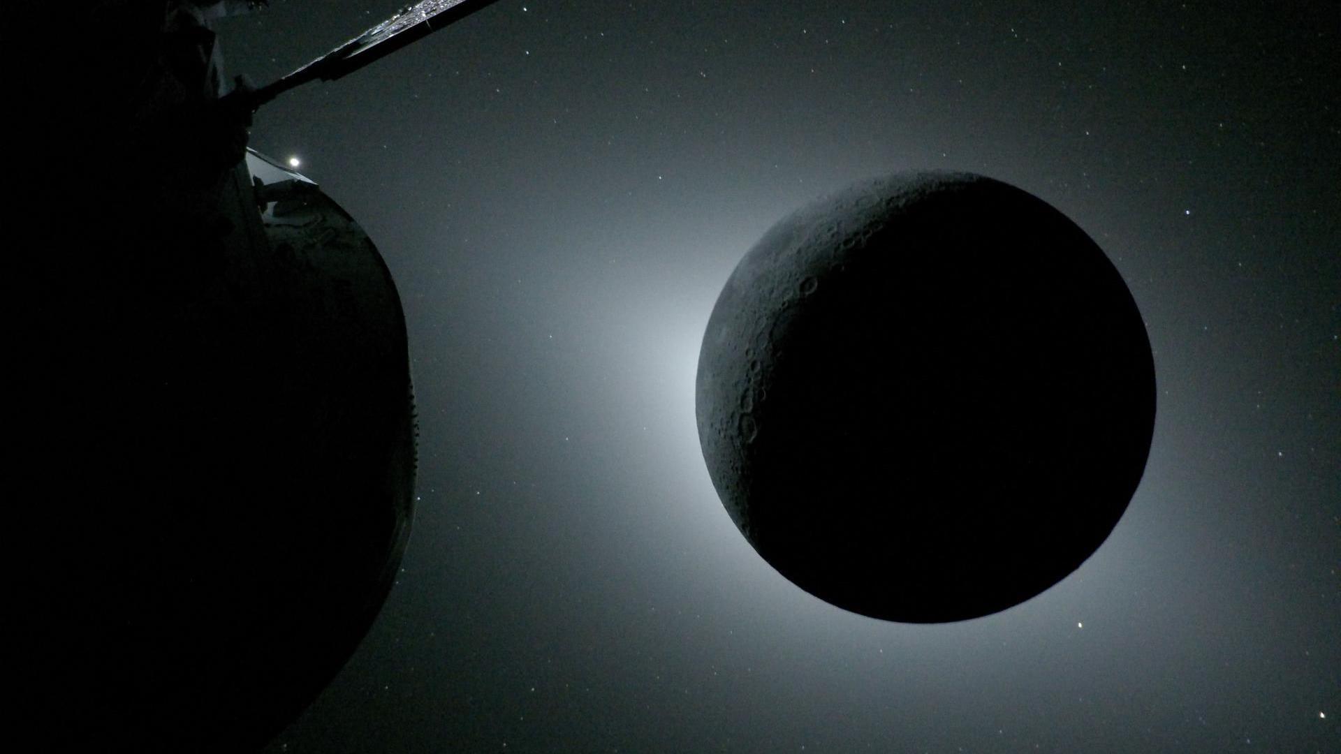 The Moon, backlit by the Sun during a solar eclipse, is photographed by NASA’s Orion spacecraft during the Artemis II mission. Orion is visible to the front on the left. Earth is reflecting sunlight at the left edge of the Moon, which is slightly brighter than the rest of the disk