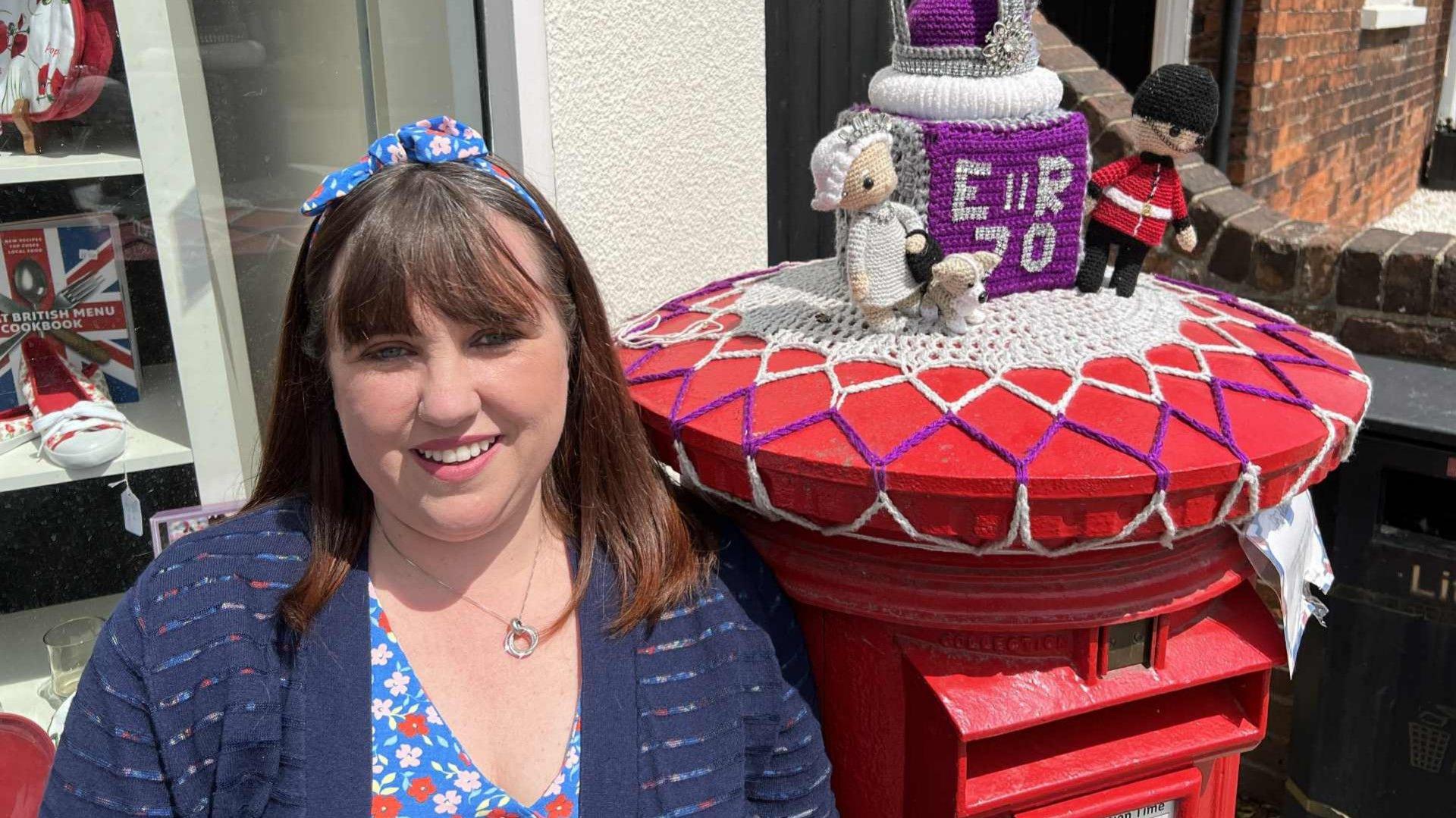 Lee-Anne Willis posing with a Queen Elizabeth anniversary-themed post box topper in 2022.