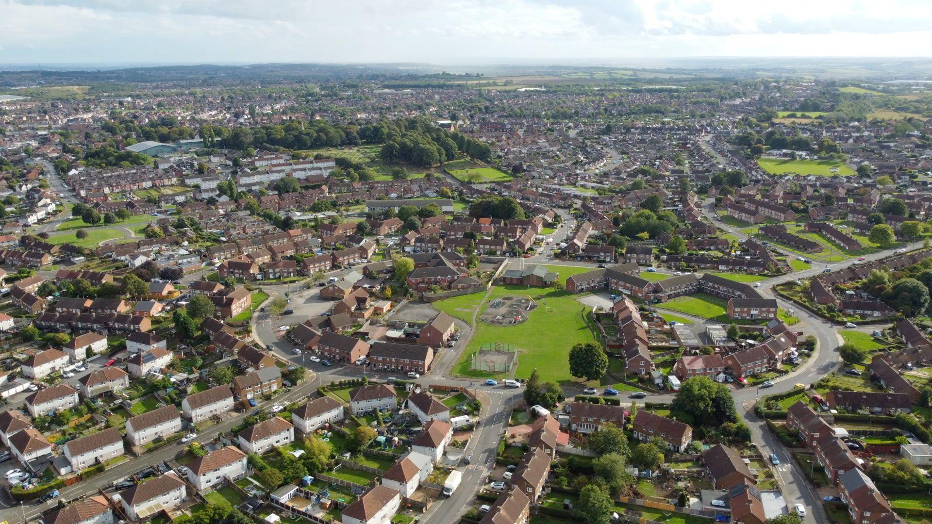 A drone shot shows a traditional housing estate build around a central circle