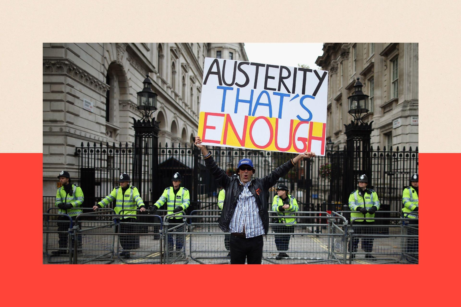 A man holds up a banner reading 'Austerity - That's Enough' outside Number 10 Downing 