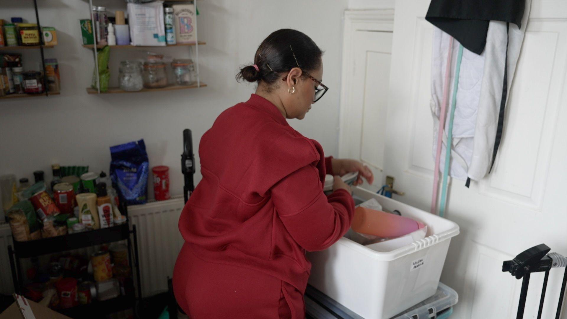 Shanice Aird, with her back to the camera, sorting out items in a box. 