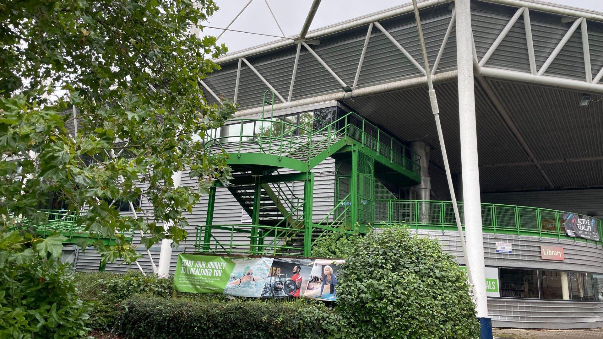 The exterior of the Link Centre in Swindon. Image shows green staircase and advertising sign.