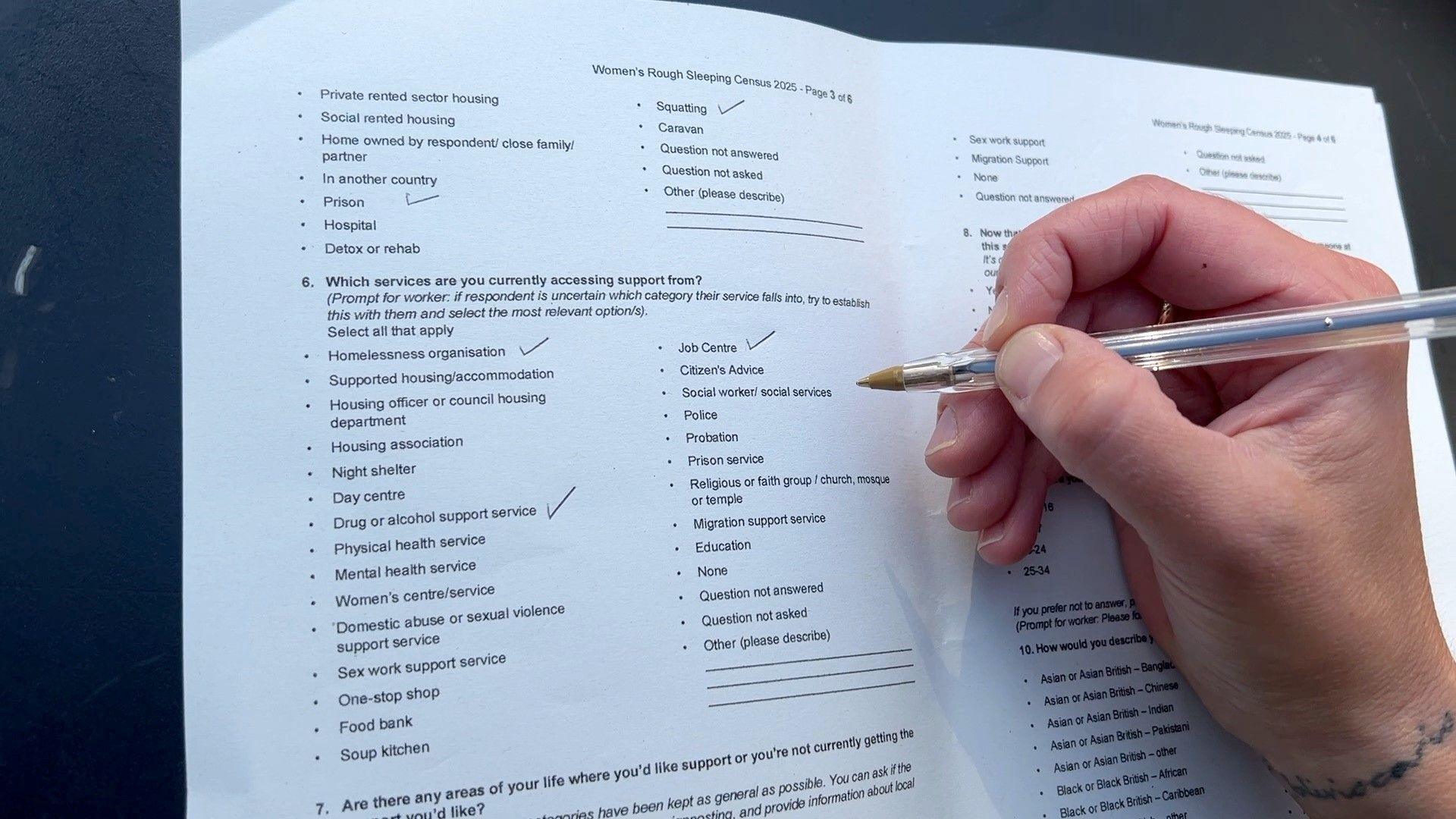 A form being filled in with a number of questions ticked by a hand visible on the right