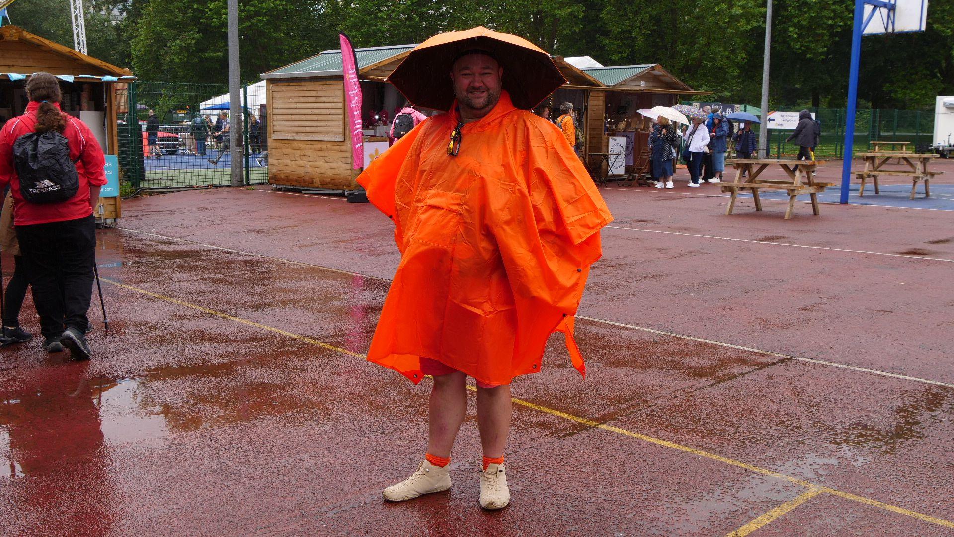 Dyn yn gwisgg poncho oren