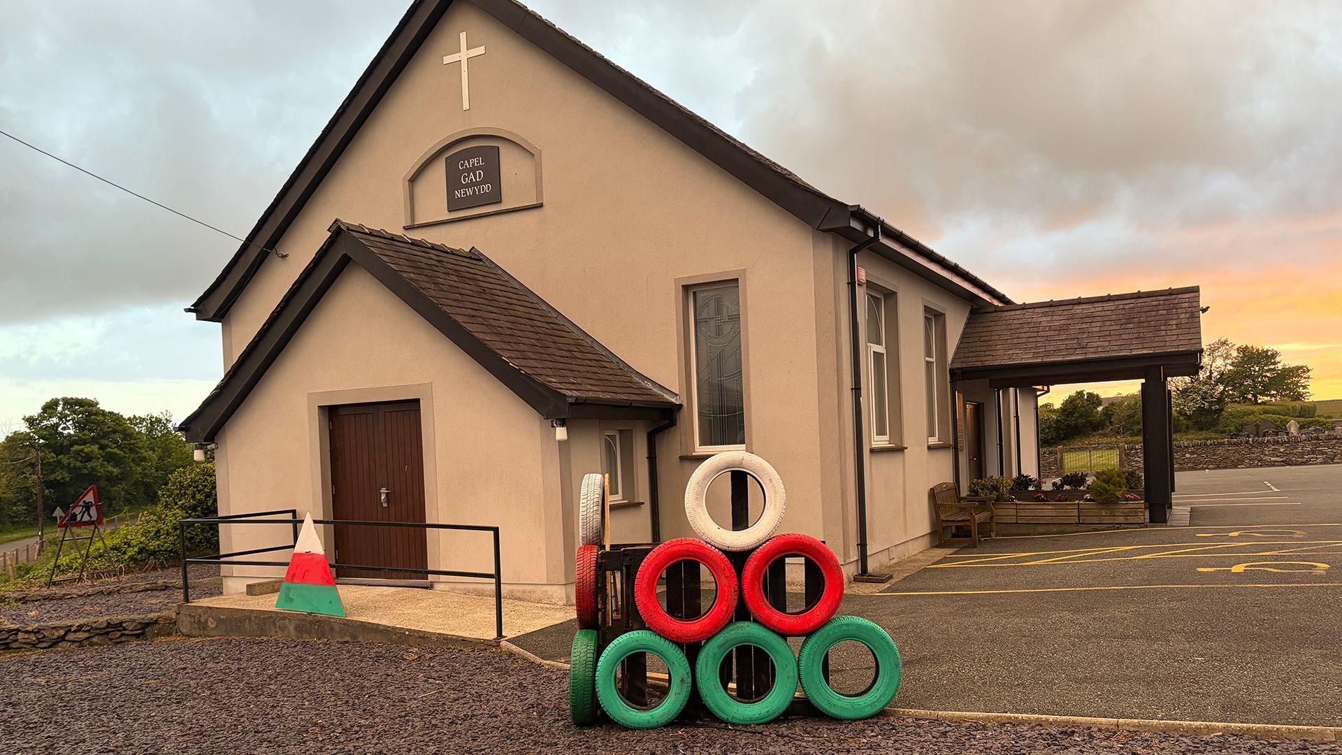 Triongl yr Urdd o flaen capel