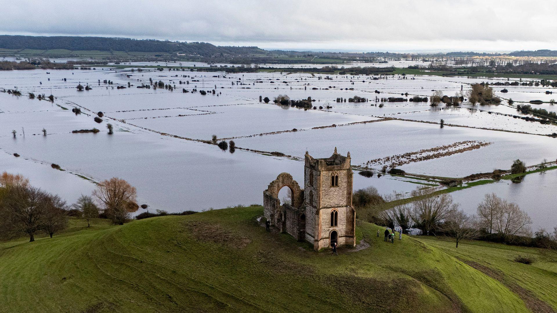 An aerial photo showing a sea of flooded fields in Somerset and in the foreground is a hill with a church on the top