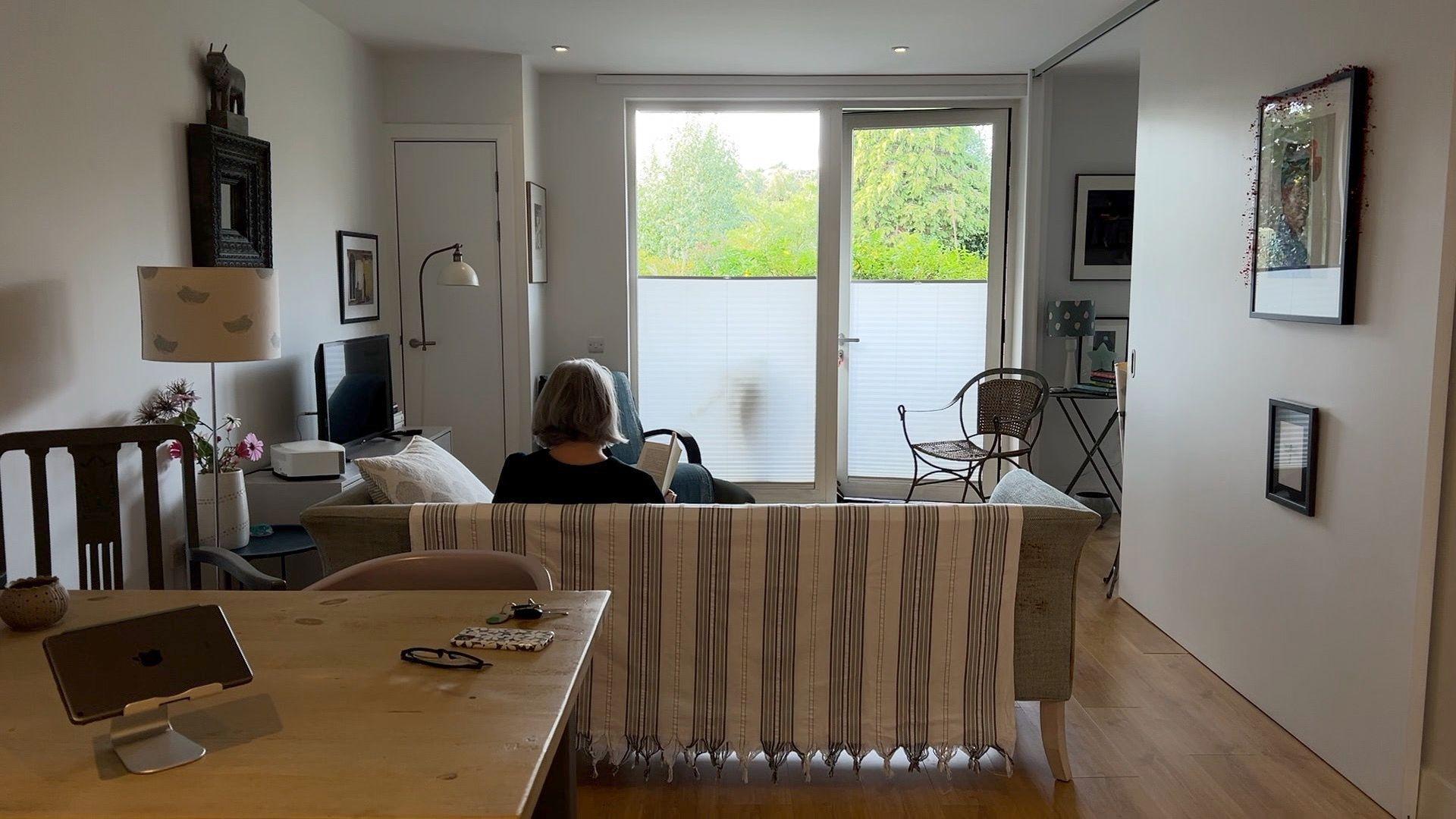 Jude Tisdall reads a book in her flat 