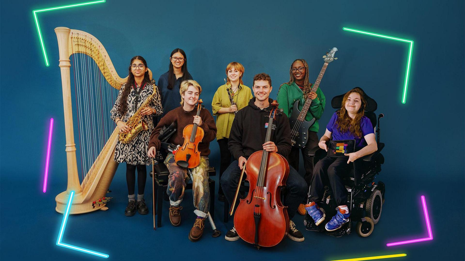 A group of musicians pose together with their instruments. They are in front of a deep blue backdrop, with neon lines framing the edges of the image in green, pink, blue and yellow. There is a large pale wooden harp on the left, next to a female musician holding a saxophone, there are two musicians sat down at the front, one holding a violin and one a cello. Behind them is a women holding a clarinet and another holding an electric bass guitar and to the right is a woman in a wheelchair holding an iPad.