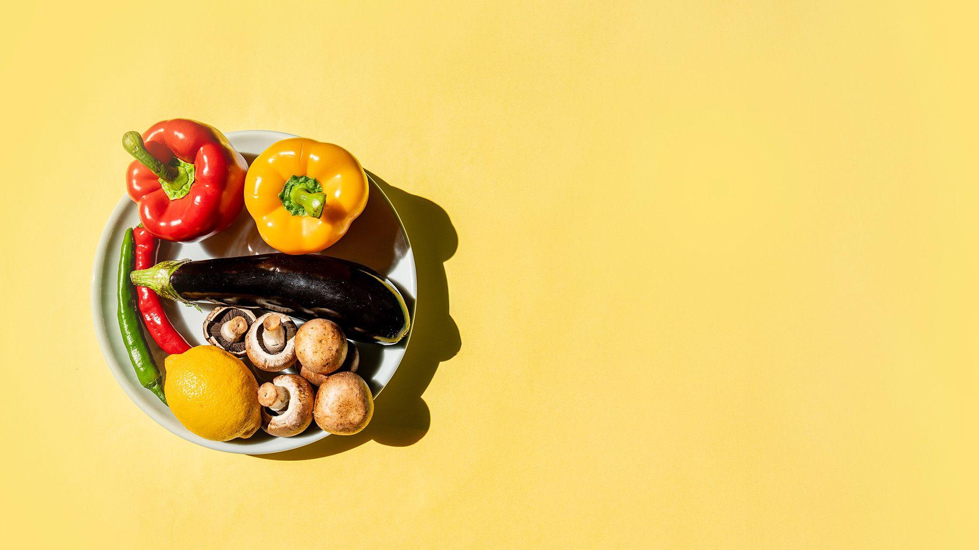 A bowl of fresh vegetables on a yellow surface
